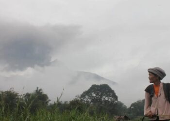 Seorang petani di Kabupaten Agam beraktivitas saat Gunung Marapi erupsi. Pusat Vulkanologi dan Mitigasi Bencana Geologi (PVMBG) menerbangkan Thermal Drone untuk pemantauan area panas di kawasan puncak gunung (Antara/Al Fatah)