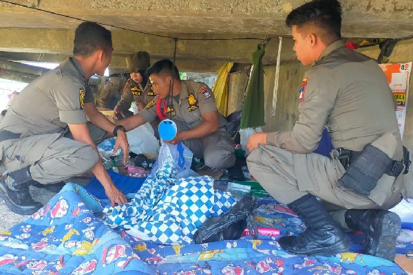 Miris, Seorang Lansia di Padang Diduga Tinggal di Kolong Jembatan 1 Petugas membersihkan sejumlah perlengkapan seorang tunawisma yang tinggal di bawah kolong jembatan. (Foto: Dok. Satpol PP Padang)