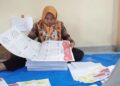 Petugas penyortiran dan pelipatan surat suara di gudang KPU Solok Selatan sedang mencermati lembar surat suara sebelum dilipat. (dok. Antara/Erik)