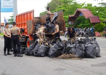 Personel kepolisian membersihkan dan mengangkut sampah yang berserakan di Pantai Padang pada Selasa (6/2/2024) pagi. (Foto: Dok. Prokopim)