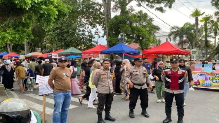 Petugas kepolisian Polresta Bukittinggi memantau kondisi untuk memastikan keamanan di pusat keramaian "pasa pabukoan" yang menjadi lokasi berburu takjil selama ramadhan, Minggu. (17/3/2024). Antara/Altas Maulana.