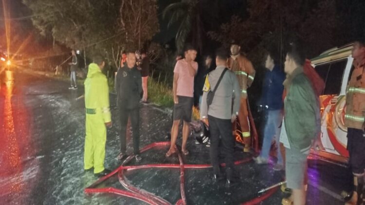 Petugas Damkar Tanahdatar membersihkan solar yang tumpah di jalan. (Foto: Dok. Polsek Batipuh)