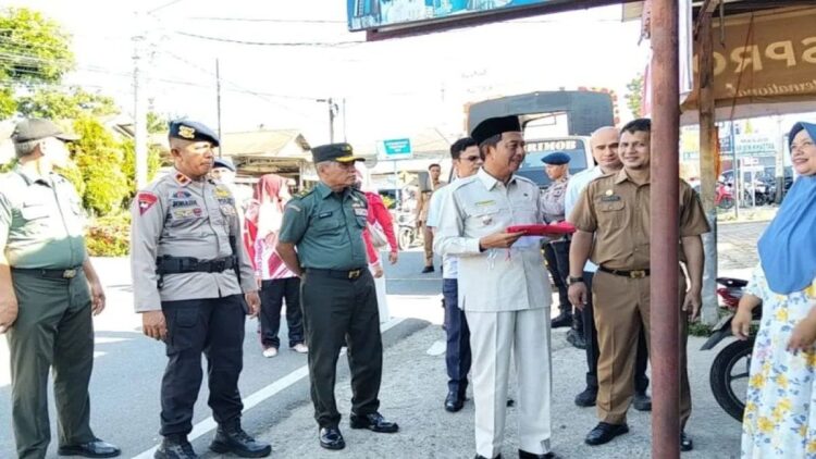 Wakil Bupati Pasaman Barat Risnawanto (pakai peci) saat membagikan Bendera Merah Putih kepada masyarakat Simpang Empat dalam rangka gerakan pembagian 10 juta bendera menyambut HUT ke-79 RI, Senin (5/8/2024). ANTARA/Altas Maulana