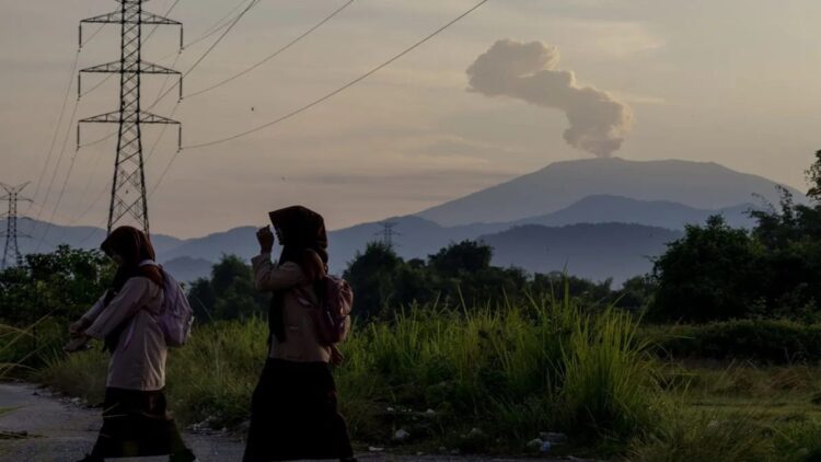 Dua orang pelajar berangkat ke sekolah dengan latar Gunung Marapi yang mengalami erupsi pada 6 Juli 2024 di Kabupaten Padangpariaman. ANTARA/Muhammad Zulfikar
