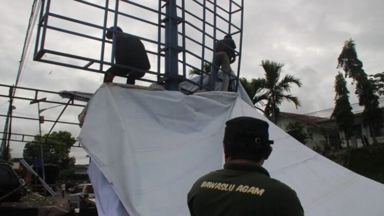 Bawaslu Kabupaten Agam menertibkan alat peraga kampanye berukuran besar di salah satu badan jalan Bukittinggi - Payakumbuh. (Antara/Al Fatah)
