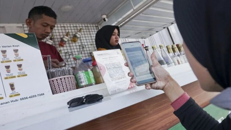 Konsumen membayar minuman yang dibelinya melalui ponsel dengan menggunakan fitur Quick Reponse Conde Indonesian Standard (QRIS) di kedai UMKM minuman, Kota Pekalongan, Jawa Tengah, Senin (9/9/2024). . ANTARA FOTO/Harviyan Perdana Putra/Spt