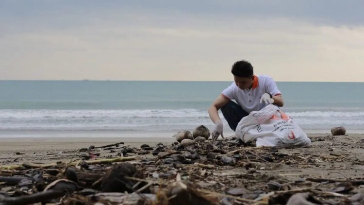 Seorang warga memilah dan mengumpulkan tumpukan sampah di salah satu sudut pantai Kota Padang, Sumatera Barat. (Antara/Fandi Yogari)
