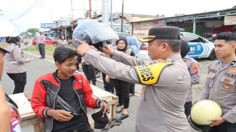Kepala Polres Pasaman Barat AKBP Agung Tribawanto saat memasangkan helm kepada pengendara dalam rangka pelaksanaan operasi keselamatan singgalang 2025. (ANTARA/HO-Humas Polres Pasaman Barat). (Pembagian helm)