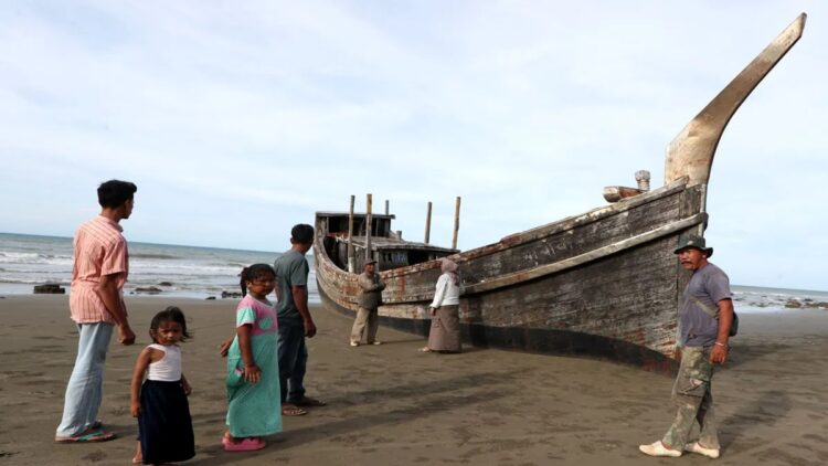 Wisatawan melihat kapal kayu yang pernah digunakan pengungsi Rohingya di Pantai Mata Ie Sepeung, Laweung, Kabupaten Pidie, Aceh, Sabtu (10/5/2025). (ANTARA FOTO/IRWANSYAH PUTRA)