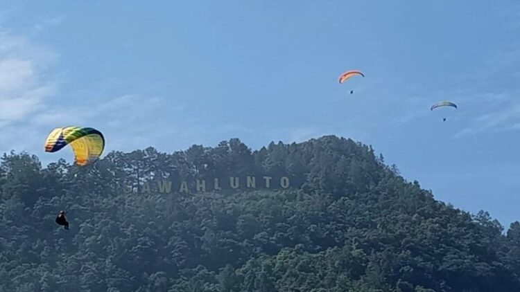 Paralayang dan Paramotor Warnai Langit Sawahlunto, Langkah Baru Sport Tourism Kota Tambang 1 Pemandangan atlet paralayang sedang terbang di samping Puncak Polan dengan landmark tulisan SAWAHLUNTO. (Antarasumbar/HO-Humas KONI Sawahlunto)