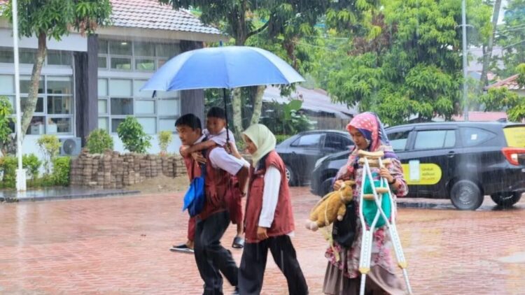 Pendamping Keluarga Harapan (PKH) saat menggendong calon siswa Sekolah Rakyat di Balai Besar Pendidikan dan Pelatihan Kesejahteraan Sosial (BBPPKS) Kementerian Sosial di Kota Padang Sumatera Barat, Senin (14/7/2025). ANTARA/Muhammad Zulfikar.