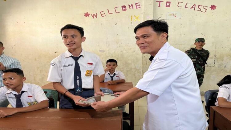 Dafati Mendrofa dari Yayasan Pondok Hilizia Permai sekaligus mitra Badan Gizi Nasional saat menyerahkan paket MBG di SMPN 1 Hiliserangkai, Kabupaten Nias, Sumatera Utara. (Radarsumbar/Putra)