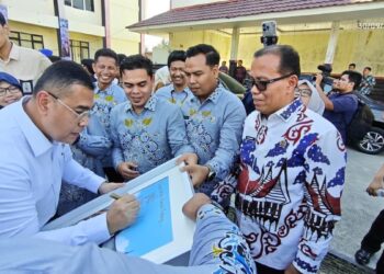 Wamen ATR/BPN, Ossy Dermawan saat menandatangi karya seni buatan pegawai BPN Padang di sela penyerahan sertifikat untuk masyarakat di Padang. (dok. Radarsumbar)